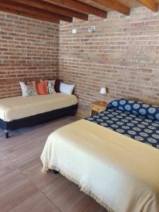 two beds in a room with a brick wall at Cabañas San Valentin in Lago Puelo