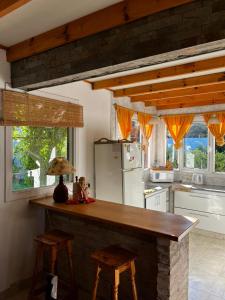 a kitchen with a counter with stools and a refrigerator at Villa Serena Deportista in Necochea