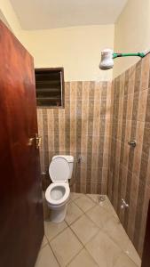 a bathroom with a toilet and a light on the wall at Noorhaven stay in Watamu