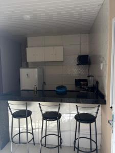 eine Küche mit drei Stühlen und einer Arbeitsplatte in der Unterkunft Flat in Japaratinga