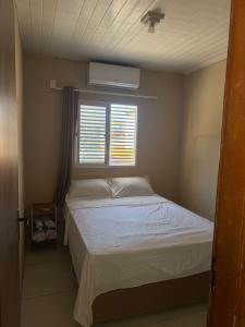 ein kleines Schlafzimmer mit einem Bett und einem Fenster in der Unterkunft Flat in Japaratinga