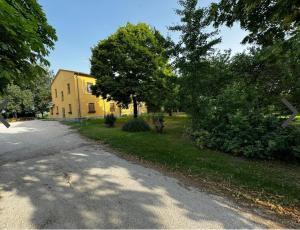 a yellow house with trees on the side of a road at B&B Tre di Cuori in Campiano