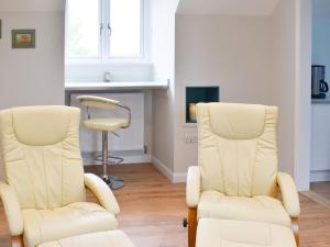 two white chairs sitting in a room with a chair at Leveret Lodge in Burgh