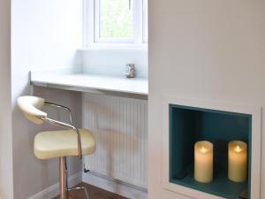 a room with a chair and a fireplace with two candles at Leveret Lodge in Burgh