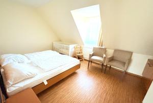 a bedroom with a bed and two chairs and a window at Boddenhof Apartment 52 - Balkon, hundefreundlich in Buschvitz