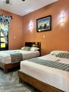 a bedroom with two beds and a picture on the wall at Hotel Rosa de los vientos in Tuxpan de Rodríguez Cano