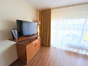 a hotel room with a television and a large window at Boddenhof Apartment 44 - Terrasse, Hund willkommen in Buschvitz