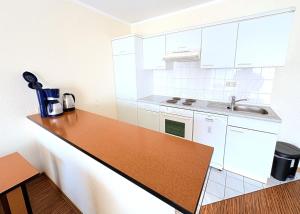 a kitchen with white cabinets and a wooden counter top at Boddenhof Apartment 46 - ebenerdig, tierfreundlich in Buschvitz