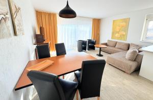 a living room with a dining table and a couch at Boddenhof Apartment 50 - modern und freundlich, viel Sonne in Buschvitz +10 photos