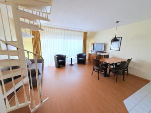 a living room and dining room with a staircase and a table at Boddenhof Apartment 54 - Balkon, Parkplatz, ruhig in Stedar