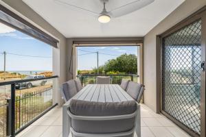 a dining room with a table and chairs and a balcony at Best Location in Woorim - Ocean Front Pool in Woorim