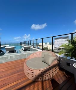 a wicker chair on a balcony with the ocean at Flat a 20 metros da praia in João Pessoa