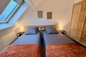 a attic bedroom with two beds and a window at Le Duplex 4p - 2 chambres, centre Compiègne in Compiègne