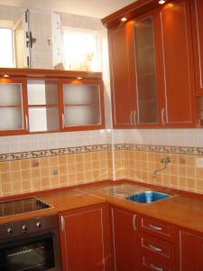 cocina con armarios marrones y fregadero azul en Accommodation Milla, en Ulcinj