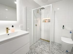 a white bathroom with a shower and a sink at The Fenway Hostel in Launceston