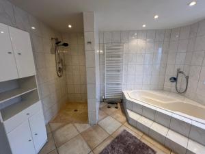 a white bathroom with a tub and a shower at Groasmückle Apartment in Tauberbischofsheim +30 photos