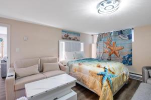 a bedroom with a bed and a couch at Beachbreeze Oceanfront 4BR1Den4BA Romantic Sunrise & Celestial Views in Mill Bay