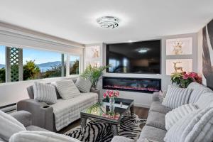 a living room with two couches and a fireplace at Beachbreeze Oceanfront 4BR1Den4BA Romantic Sunrise & Celestial Views in Mill Bay