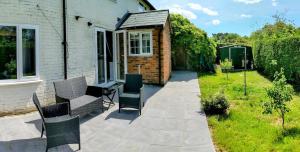 a patio with two chairs and a house at Groombridge 1 Bed self catered flat, can sleep 2 in Groombridge