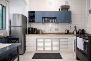 a kitchen with blue cabinets and a stainless steel refrigerator at Mirante Luz Floripa in Florianópolis