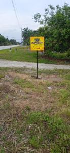 a yellow sign sitting on the side of a road at Homestay D'Kampong in Teluk Intan