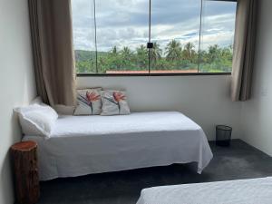 a bedroom with a bed and a large window at Pousada dos Bougainvilles in Manhã