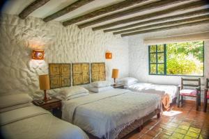 a bedroom with three beds and a window at Casa San Nicolas in Villa de Leyva