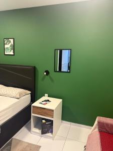 a bedroom with a green wall with a bed and a table at Loft Dominguinhos in Campina Grande