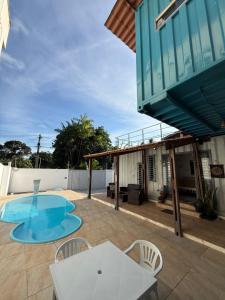 a patio with a table and chairs and a swimming pool at Conteiner House in Pipa