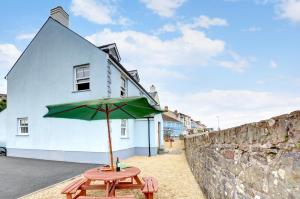 a picnic table with an umbrella in front of a building at 5 Bed in Amroth oc-pw9067 in Amroth