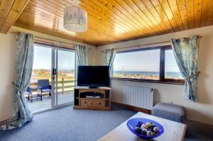 a living room with a television and a view of the ocean at 4 Bed in Moelfre oc-wai202 in Moelfre