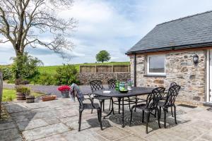 a patio with a table and chairs in front of a stone cottage at 3 Bed in Corwen oc-fl009 in Derwen