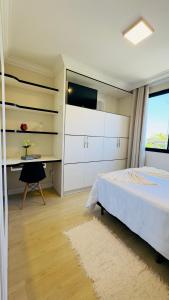 a bedroom with a bed and a desk and a television at Apê com vista para o mar e clima animado in Vitória