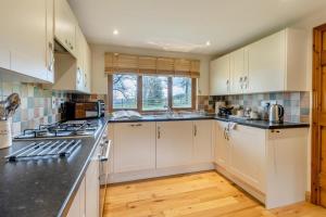 a kitchen with white cabinets and black counter tops at 2 Bed in Caersws oc-waa345 in Trefeglwys