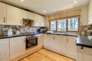 a kitchen with white cabinets and black counter tops at 2 Bed in Caersws oc-waa345 in Trefeglwys +9 photos