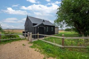 a black barn in a field with a fence at 1 Bed in Wickhambrook oc-tosh in Wickhambrook