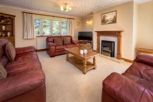 a living room with leather couches and a fireplace at 5 Bed in Bryncroes oc-llecyn in Pwllheli