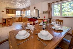 a kitchen with a wooden table with plates and wine glasses at 5 Bed in Bryncroes oc-llecyn in Pwllheli