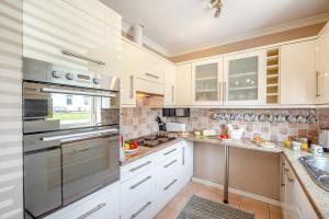 a kitchen with white cabinets and stainless steel appliances at 4 Bed in Morfa Nefyn oc-bow10 in Morfa Nefyn