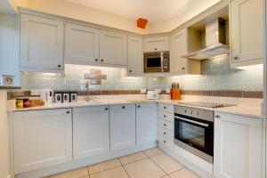 a white kitchen with white cabinets and appliances at 2 Bed in Barmouth oc-wah698 in Talybont +12 photos
