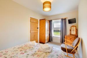 a bedroom with a bed and a chair and a window at 2 Bed in Barmouth oc-wah698 in Talybont