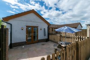 a wooden fence with an umbrella and a patio at 2 Bed in Gower oc-hh486 in Penclawdd