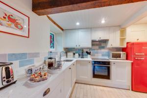 a kitchen with white cabinets and a red refrigerator at 3 Bed in Benllech oc-24195 in Benllech +13 photos