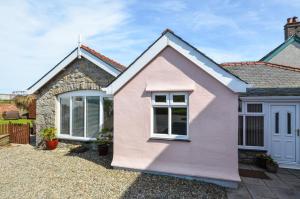 a pink house with a gravel driveway at 3 Bed in Benllech oc-24195 in Benllech
