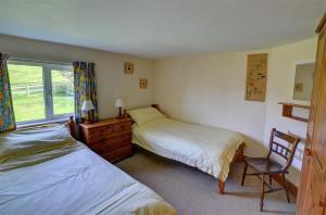 a bedroom with two beds and a chair and a window at 4 Bed in Presteigne oc-wak235 in Norton