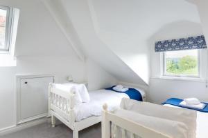 a white room with a crib and a bed and a window at 4 Bed in Masham oc-ds1007 in Masham