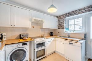 a kitchen with white cabinets and a washer and dryer at 2 Bed in Kendal oc-gl097 in Kendal
