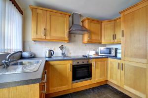 a kitchen with wooden cabinets and a sink at 2 Bed in Welshpool oc-wab256 in Berriew +3 photos