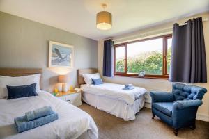 a bedroom with two beds and a chair and a window at 3 Bed in Pwllheli oc-penmae in Pwllheli