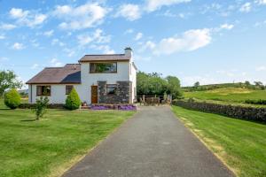 a white house with a stone wall and a driveway at 3 Bed in Pwllheli oc-penmae in Pwllheli